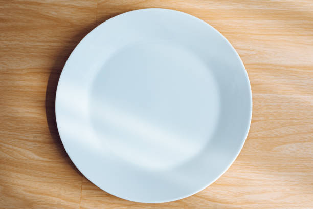 istock 1 empty white plate with a wooden background. 1954705946