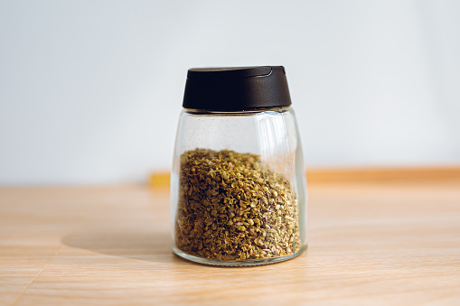 Oregano powder in a small jar, Wooden background and white background.