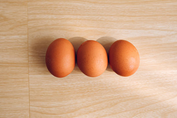 istock 3 chicken eggs with a wooden background. 1954705974