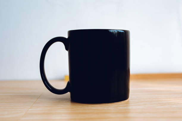 istock 1 black mug with a wooden floor and white background. 1954705990