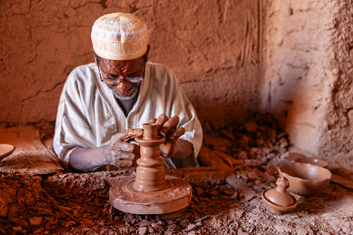 Moroccan potter working in the workshop on the pottery wheel near Ouarzazate, Morocco.