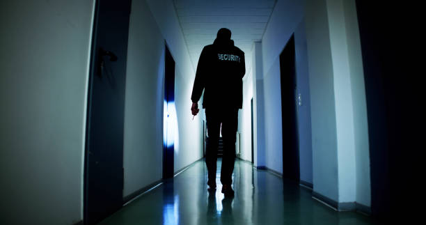 istock Male Security Guard Holding Flashlight Standing In Corridor 1954715734