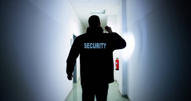 istock Male Security Guard Holding Flashlight Standing In Corridor 1954715735