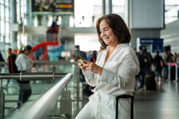 istock Senior woman using cell phone at airport 1954722317