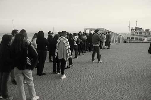 Lisbon, Portugal - November 1, 2023: people queue up to catch a ferry in Lisbon downtown.