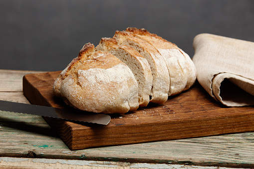 Still life: bread and knife on a wooden board. Selective focus