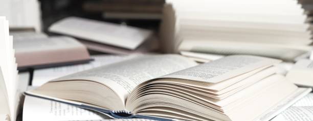 istock stack of books, close up. Open book on the table in library. Back to school concept. Open book on table with blur bookshelf background 1954764755