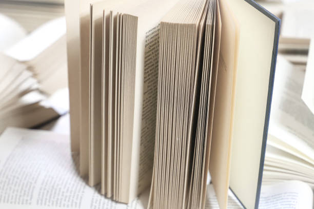istock stack of books, close up. Open book on the table in library. Back to school concept. Open book on table with blur bookshelf background 1954765349
