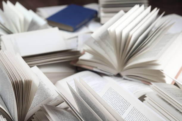 istock stack of books, close up. Open book on the table in library. Back to school concept. Open book on table with blur bookshelf background 1954765903