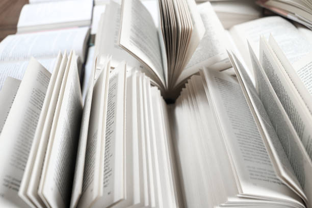 istock stack of books, close up. Open book on the table in library. Back to school concept. Open book on table with blur bookshelf background 1954765912