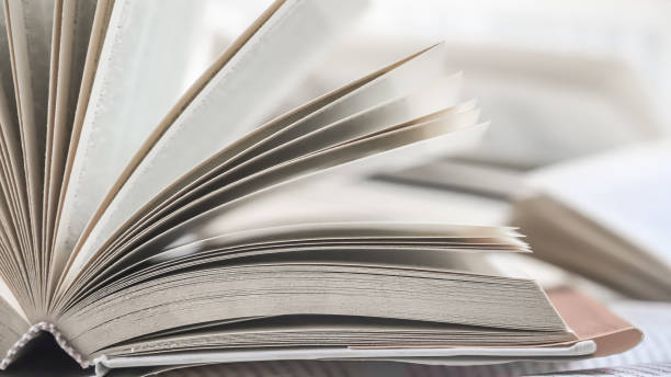 istock stack of books, close up. Open book on the table in library. Back to school concept. Open book on table with blur bookshelf background 1954768040