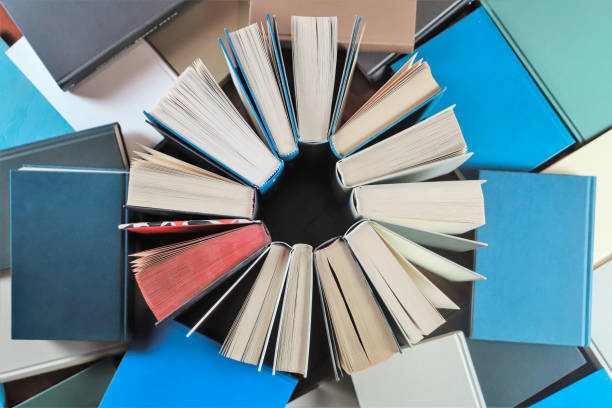 istock stack of books, close up. Open book on the table in library. Back to school concept. Open book on table with blur bookshelf background 1954768594