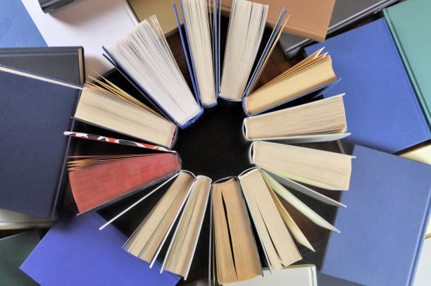 istock stack of books, close up. Open book on the table in library. Back to school concept. Open book on table with blur bookshelf background 1954768599