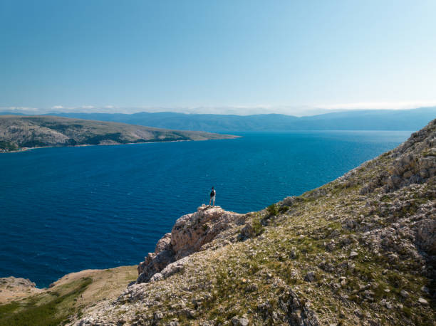 Man standing above Baska bay (Krk island, Croatia). View from the mountain.