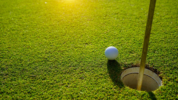 top view of a golf ball on green course at hole. - golf golf flag sunset flag zdjęcia i obrazy z banku zdjęć