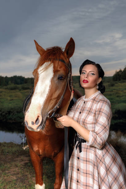 Young beautiful woman in a retro dress next to a horse.
