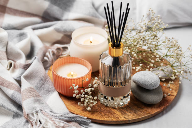 Cozy home atmosphere. Home liquid fragrance in glass bottle Cozy home atmosphere. Home liquid fragrance in glass bottle and scented candle on tray. home diffuser stock pictures, royalty-free photos & images