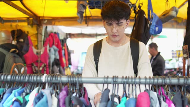 Young man buying clothes on the street market