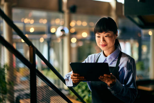 istock A focused Asian waitress looking at the online menu, over the digital tablet. 1954798759