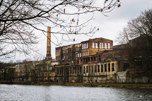 Abandoned multi-story brick factory building with broken glass windows.