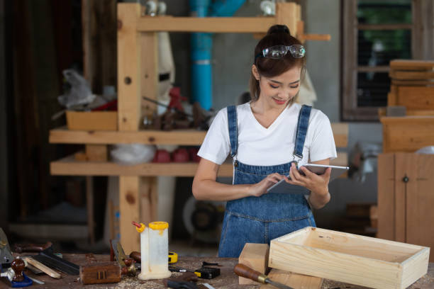 istock Young woman is training to be a carpenter in workshop. Carpenter working with equipment on wooden table. woman works in a carpentry shop. 1954827969