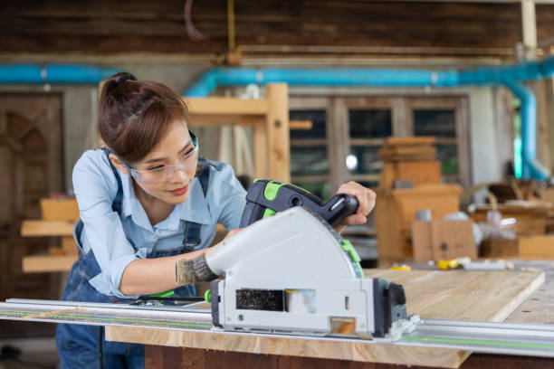 istock Young woman is training to be a carpenter in workshop. Carpenter working with equipment on wooden table. woman works in a carpentry shop. 1954827980