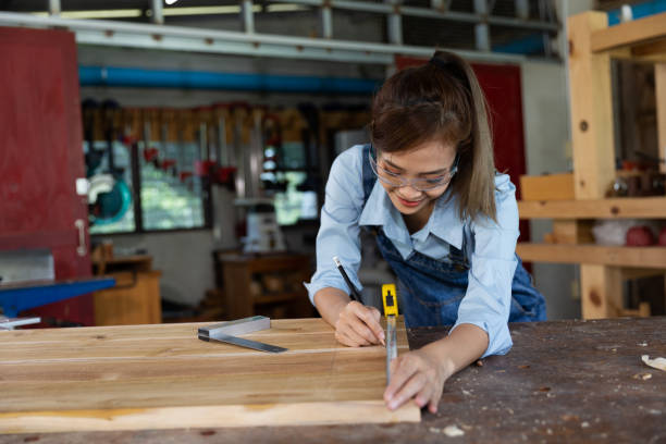 istock Young woman is training to be a carpenter in workshop. Carpenter working with equipment on wooden table. woman works in a carpentry shop. 1954827981