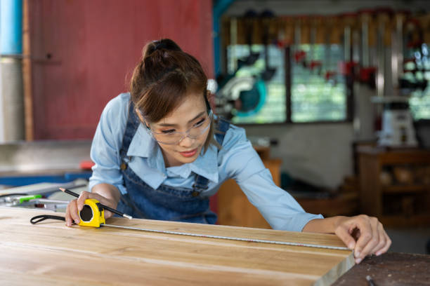 istock Young woman is training to be a carpenter in workshop. Carpenter working with equipment on wooden table. woman works in a carpentry shop. 1954827983
