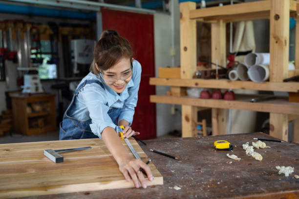 istock Young woman is training to be a carpenter in workshop. Carpenter working with equipment on wooden table. woman works in a carpentry shop. 1954827984