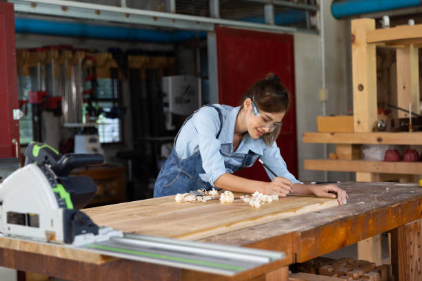 istock Young woman is training to be a carpenter in workshop. Carpenter working with equipment on wooden table. woman works in a carpentry shop. 1954828517