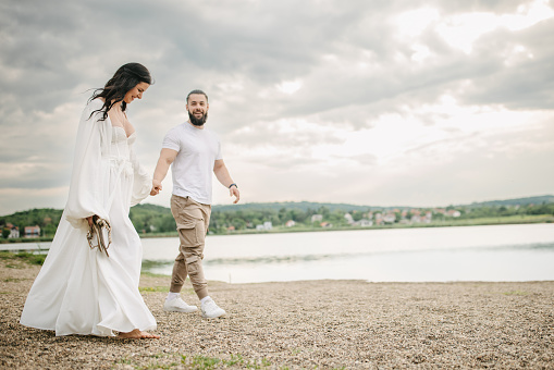 Happy young couple walking by the lake outdoors.