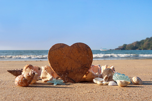 Small pebbles set together in a shape of heart on beach at sunset.