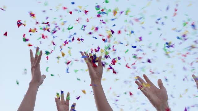 Event, people or confetti with sky background, hands and party with decoration or wow. Closeup, outdoor or group with birthday or excited with glitter, promotion or energy with victory or celebration