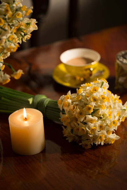 Daffodil flowers closeup detail in a warm setting with candle and a cup of tea stock photo