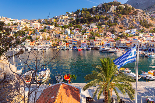 View of colorful traditional houses and fishing boats in the fishing village of Symi at sunset.. Greece. Dodecanese.