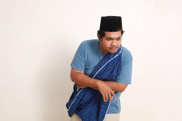 istock Curious young asian muslim boy standing while looking aside down. Isolated on white 1954897702