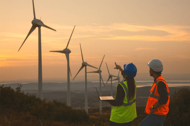 istock Young maintenance engineer team working in wind turbine farm at sunset 1954910041