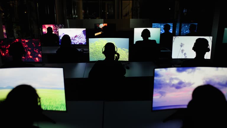 Computer, back and surveillance at night with people in office for safety, security or global monitoring. Headphones, video and cctv with staff watching live feed on shift in workplace control room