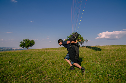 Paraglider pilot running on field, getting ready for flight , closeup shot