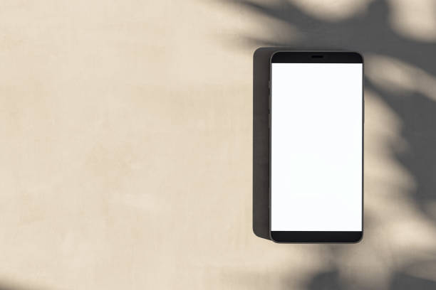 istock Close up of empty white cellphone on light surface with leaf shadows. Presentation concept. Mock up, 3D Rendering. 1954981544