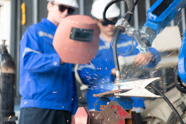 Two construction workers are welding large iron for the building foundation.