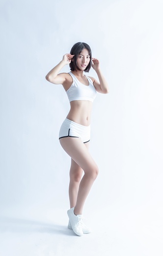 Asian female in sportswear posing on white background