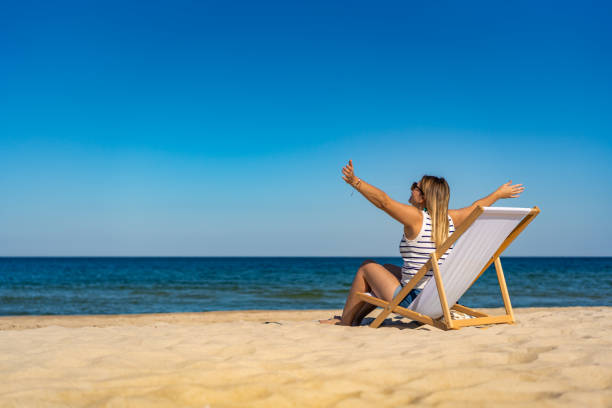 istock Woman sitting on sunbed relaxing on beach 1954995268