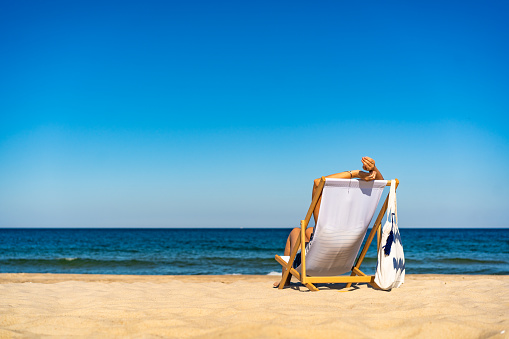 Woman sitting on sunbed relaxing on beach