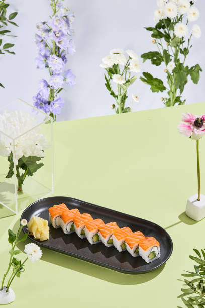 istock Artistic sushi composition with Philadelphia roll featuring salmon, avocado, and cheese in a floral summer setting 1954997861