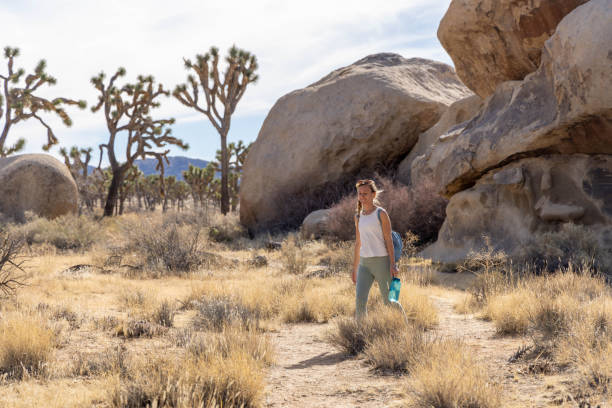 istock Lone Wanderer: A Woman's Solo Hike with Water in Hand 1955002689