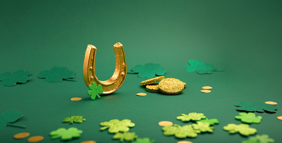 Portrait of man wearing green wig and hat for St. Patrick's day with clover leaves and having a green beer sit at his dining table