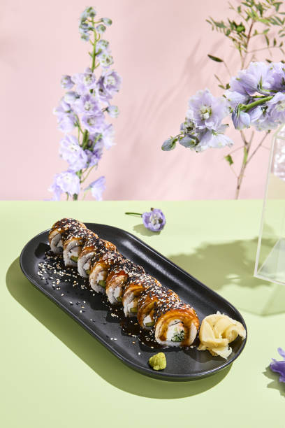 istock Surreal summer sushi scene with Canada roll, eel, sesame seeds and artistic floral composition 1955007058