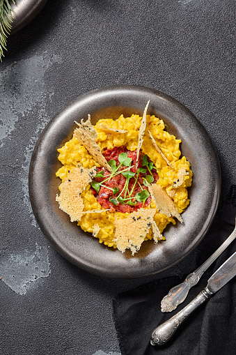 Milanese-style risotto with beef tartare and Parmesan crisps, an upscale infusion of Italian flavors.