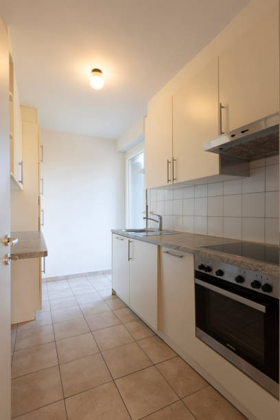 istock Old white kitchen with an oven, sink and cabinets. Light on 1955018288